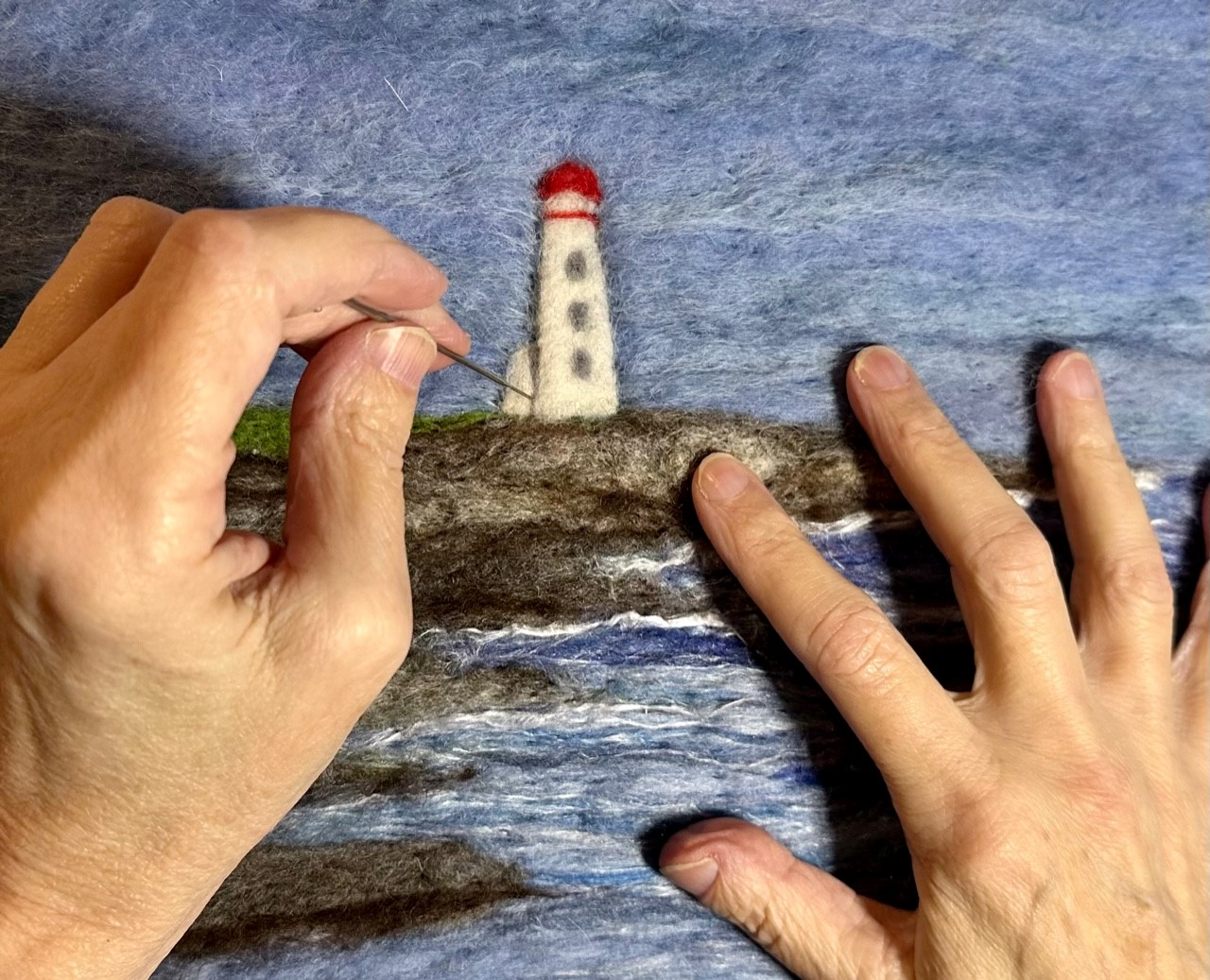 hands needle felting a landscape art work