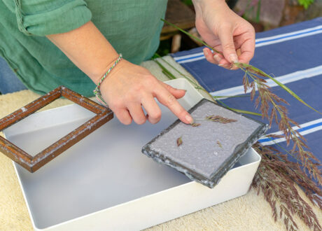 Woman holding frame for making paper sheets from waste paper pulp.